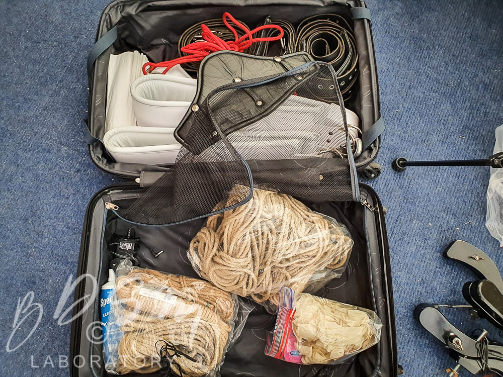 Suitcase of ropes, leather straps, chains, gags, and collars, along with various fetish kit