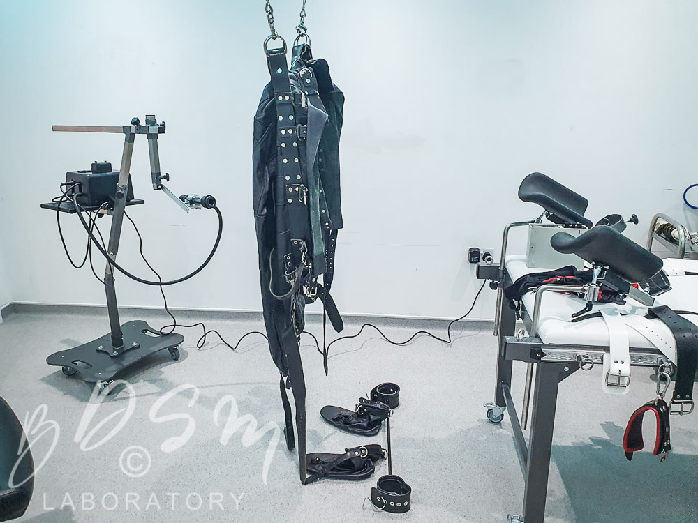 “Leather The Storm” 1 leather strait jacket suspended from the ceiling, boot cuffs and kink kit