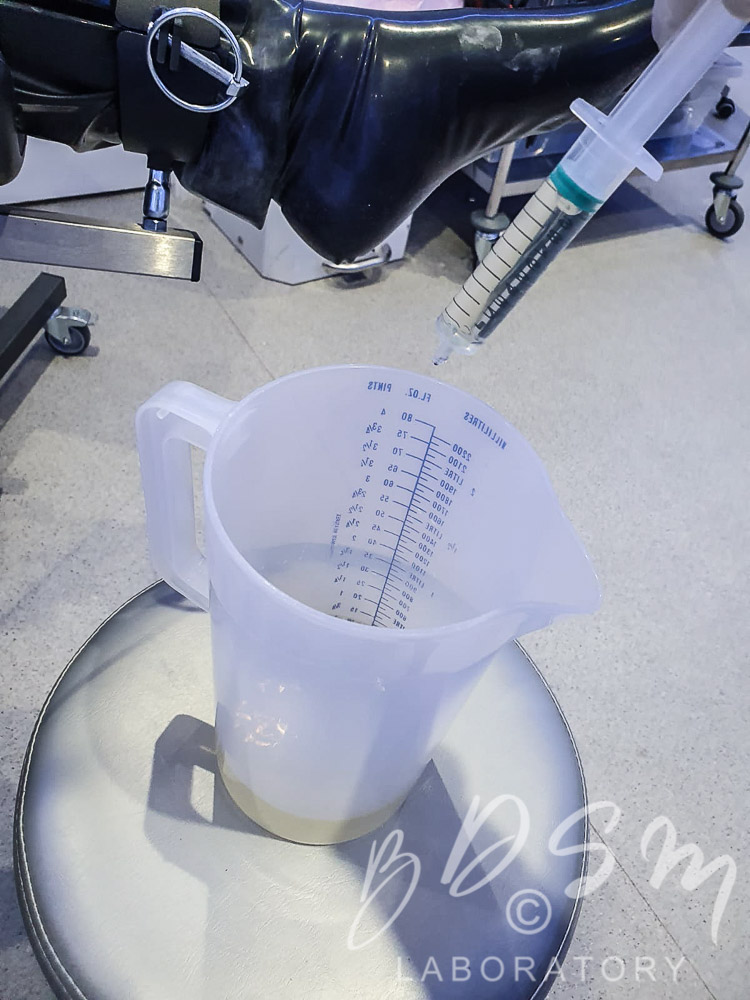 Plastic measuring jug and syringe containing piss