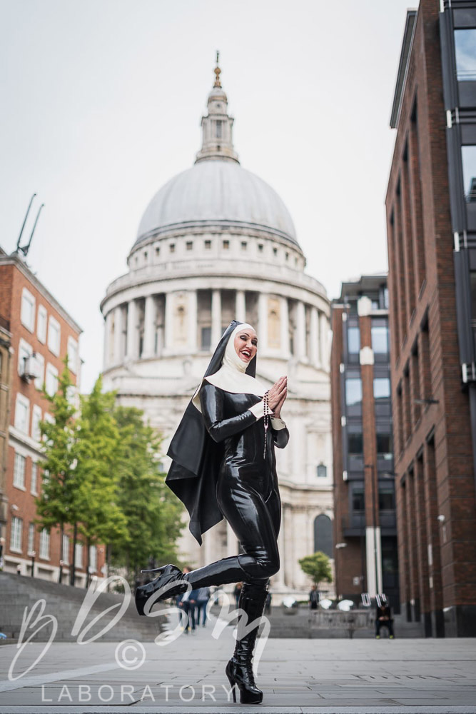 Mistress Miranda smiling dressed as a Latex Nun, in front of St Pauls Cathedral, London