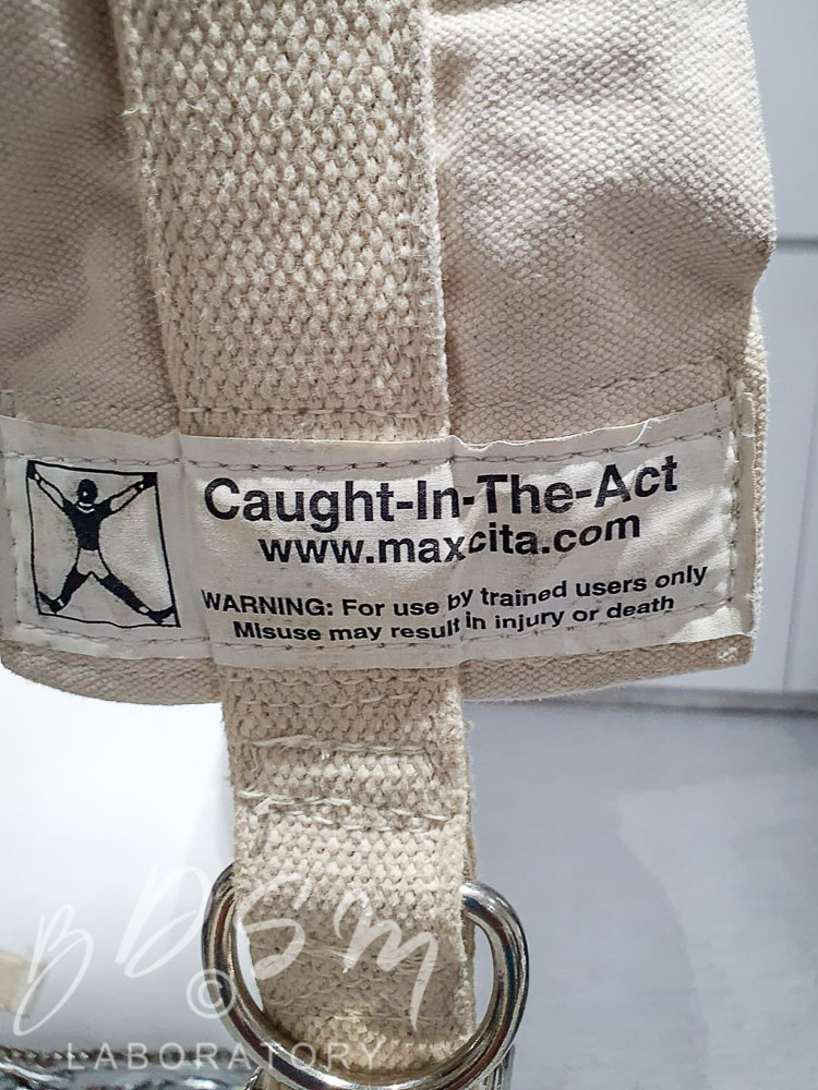 close up of White canvas straight jacket Caught in the act label