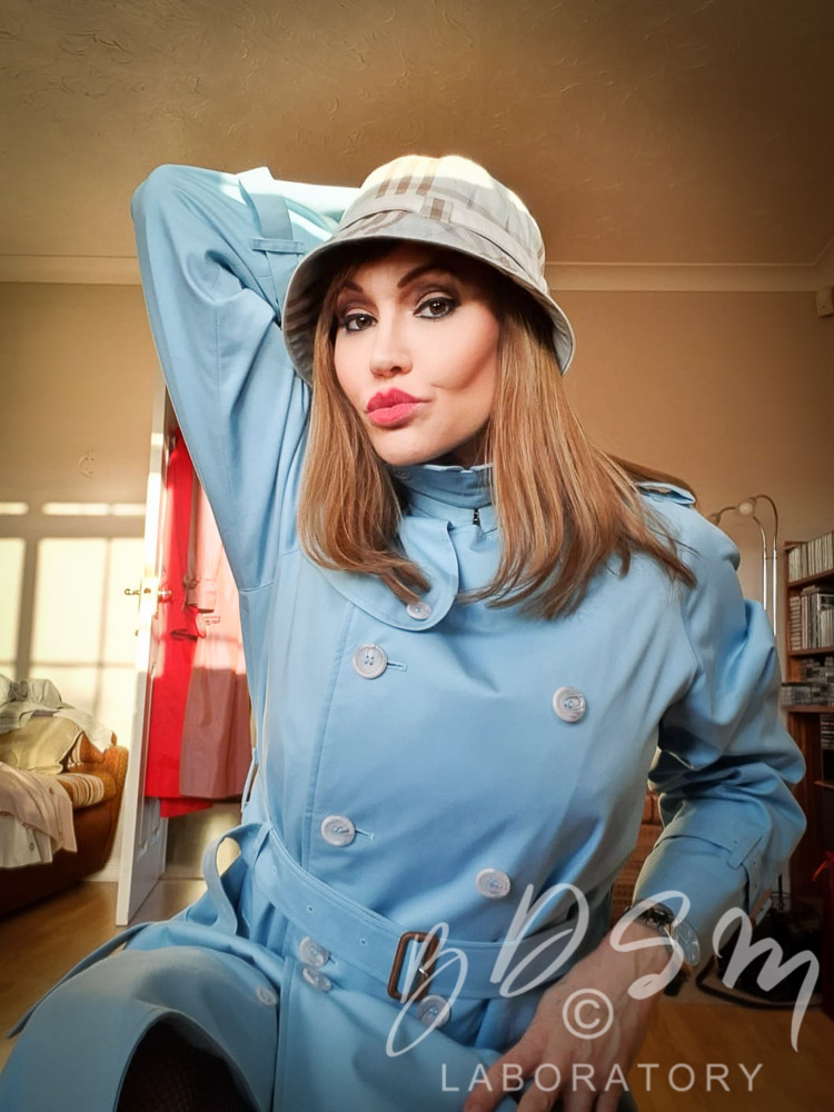 Mistress Miranda wearing a blue Mackintosh and hat